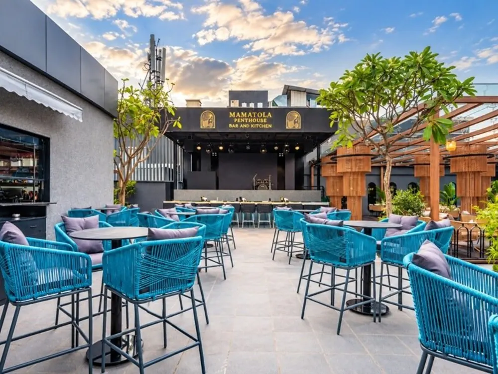 Outdoor café terrace with blue rope bar chairs and high tables at Mamalola, Hyderabad