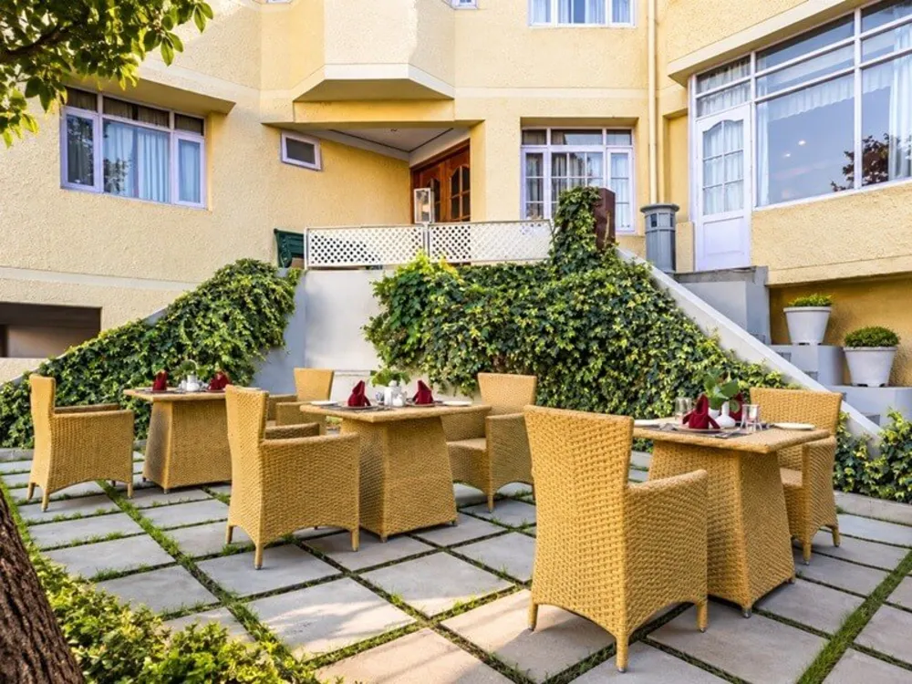 Yellow wicker dining chairs and tables on a hotel garden terrace in Shimla
